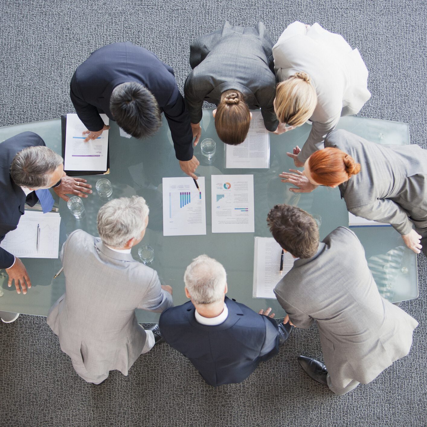 Business meeting with documents on glass table